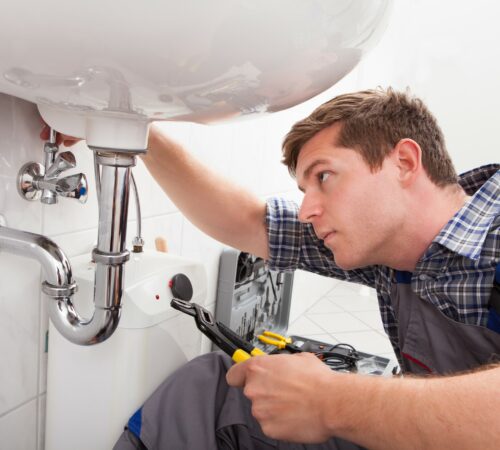 Portrait of male plumber fixing a sink in bathroom